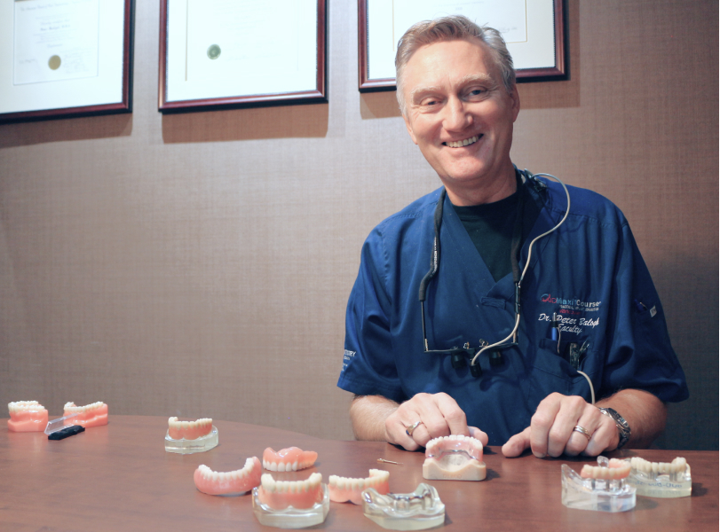 A photograph of experienced implant dentist Dr. Peter Balogh alongside several options for dentures and full mouth dental implants in Burnaby at VCCID