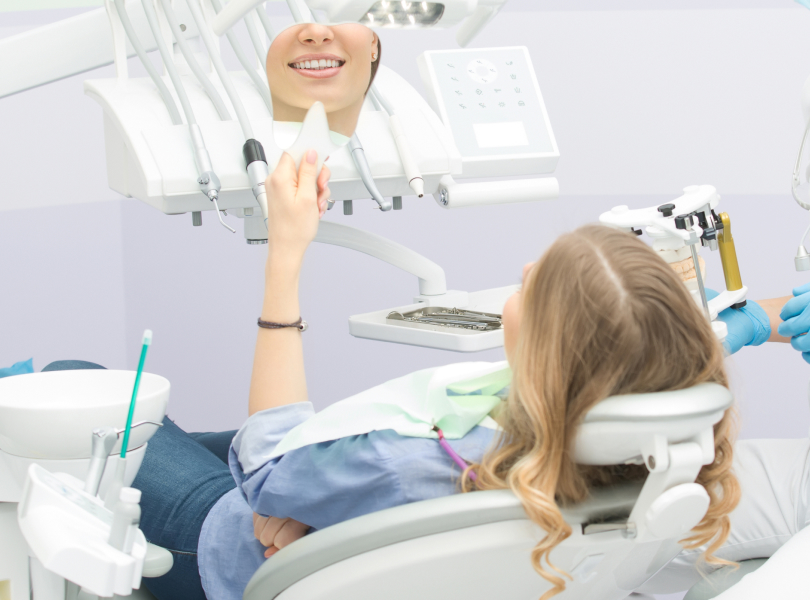 A patient seated in a dental chair admiring a bright, clean smile like patients do after receiving teeth cleaning in Burnaby at VCCID